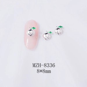 Macro detail of 8x8mm peach-shaped alloy nail charms with green enamel leaf accents
