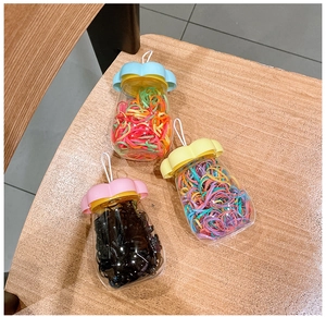 Detailed view of three jars with colorful elastic hair bands and flower-shaped lids