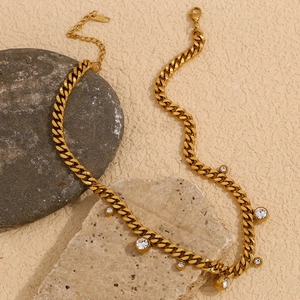 Detailed shot of golden Cuban chain necklace with round zircon pendants on a textured background