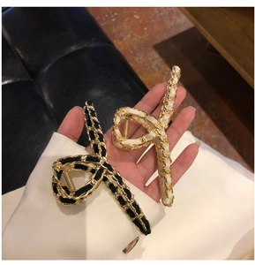 Detail of elegant black and white hair claws with woven golden chain and ribbon textures