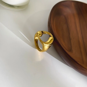 Anello in acciaio inossidabile dorato con design organico su vassoio di legno