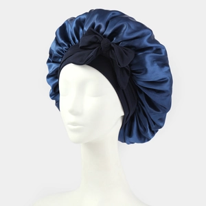 Detail view of navy blue satin night cap with black bowknot on a white mannequin head