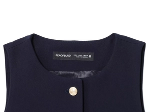 Détail de l'étiquette et du bouton doré sur ce gilet sans manches bleu marine