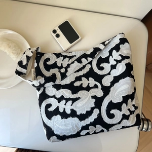 Close-up of black and white cotton-linen embroidered bag with raw edges and simple wish label