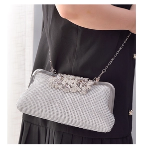 Detail of silver rhinestone evening clutch with leaf-shaped metal clasp and chain strap