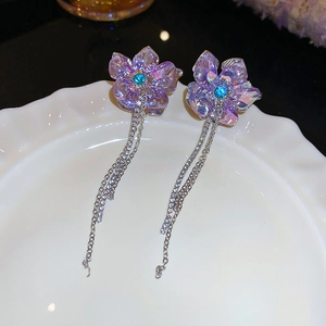 Detailed shot of purple flower earrings with blue zircon and long silver chain tassels