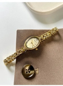 Gros plan d'une montre ovale vintage dorée avec chiffres romains et bracelet en relief