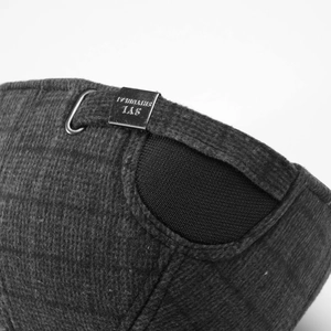 Macro detail of dark grey wool texture and adjustable metal buckle on winter baseball cap