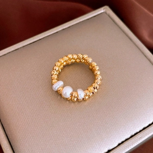 Macro shot of gold beaded ring band featuring three elegant white pearls on satin