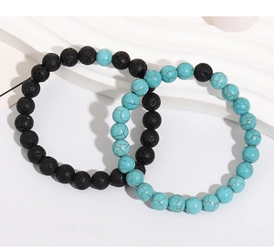 Close-up of beaded turquoise and volcanic stone bracelets on a white wave pedestal