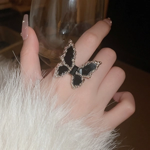 Close-up of a minimalist black butterfly ring with silver-edged wings on finger