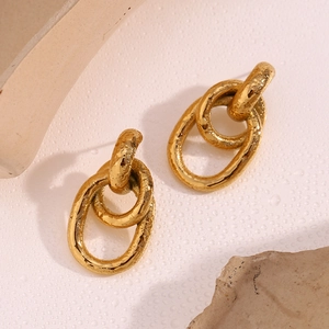 Gros plan de boucles d'oreilles dorées 18K en forme d'O avec une texture martelée