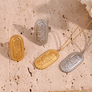 Artistic layout of gold and silver vintage floral embossed rings and necklaces on stone
