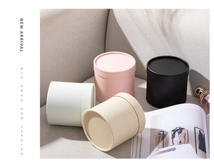 Miniature round flower gift boxes in white, pink and black on a modern fabric sofa