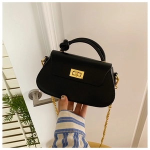 Detail of black leather handbag featuring a gold metal twist lock and elegant chain strap