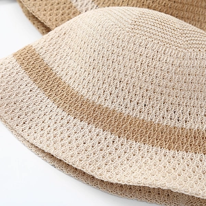 Detail of hollow knit sun hat featuring beige weave texture and brown decorative stripe