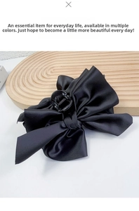Macro detail of large black satin bow hair claw clip with smooth texture and sturdy grip