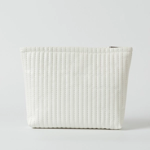 Close-up of white quilted waterproof makeup bag with vertical stitching and silver zipper
