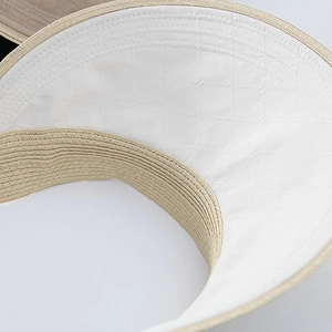 Macro shot of sun hat brim with beige woven texture and white geometric lining detail