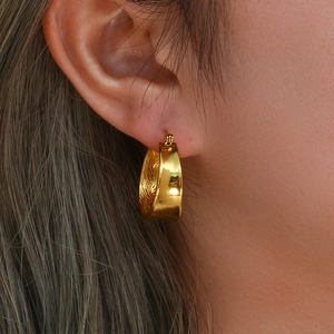 Chic gold-plated wide hoop earrings displayed on ear for a modern geometric look