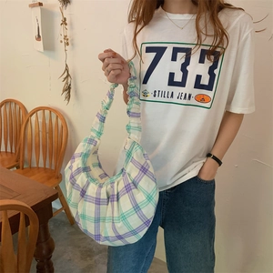 Detail of green plaid canvas shoulder bag featuring a unique pleated handle design