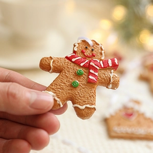 Resin gingerbread man Christmas ornament with red scarf held in a warm home setting