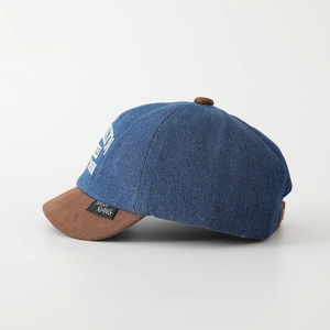 Close-up of denim patchwork baseball cap with side print and woven label detail