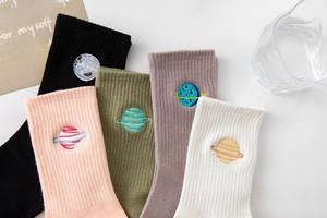 Close-up of cotton crew socks featuring colorful planet embroidery and rib knit texture
