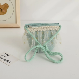 Détail d'un petit sac en paille vert menthe avec dentelle blanche et tulle à pois doux