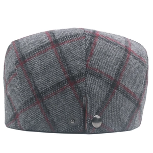 Close-up of grey and red plaid wool fabric and metal buckle on the flat newsboy cap