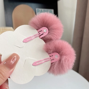 Close-up of pink faux rabbit fur pom pom hair clips on cloud-shaped display card