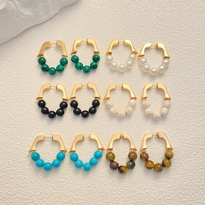 French vintage gold hoops with colorful gemstone beads shown on a textured white stone base