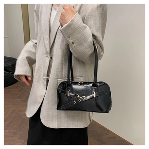 Detail of glossy black patent leather bowling bag with gold hardware held by a model