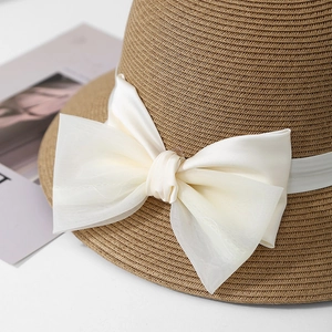 Détail du chapeau de paille avec tissage fin et un grand nœud décoratif couleur crème