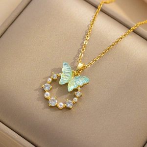 Golden butterfly necklace with iridescent blue wings, pearls, and zircons on jewelry box