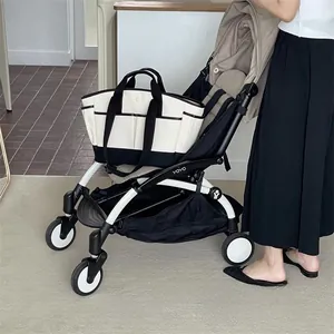 Detail view of canvas diaper bag with front pockets attached to a stroller handlebar