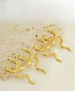 Detailed close-up of golden snake earrings showing scale texture and polished mirror finish