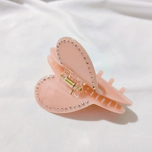 Dettaglio del fermaglio per capelli a cuore in acetato rosa con strass in cristallo