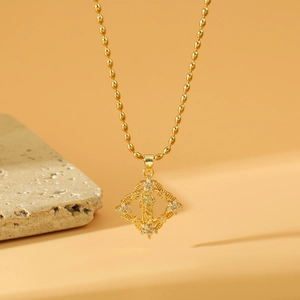 Gold plated portrait pendant necklace with geometric frame and beaded chain on marble