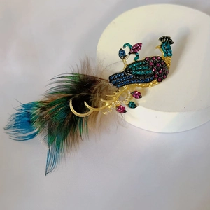 Detailed close-up of an elegant peacock brooch with colorful crystals and natural feathers