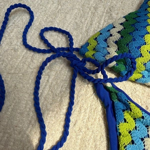 Détail du motif crocheté ondulé bleu et des liens tressés sur le haut de bikini doublé