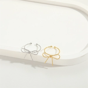 Minimalist bow-shaped open rings in gold and silver finishes on a white tray