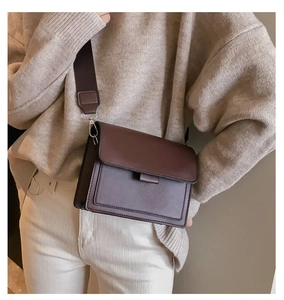 Detail of a dark brown crossbody flap bag with a wide strap on a model outfit