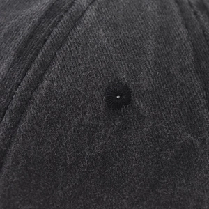 Detailed macro view of embroidered eyelet and reinforced stitching on dark grey wool cap