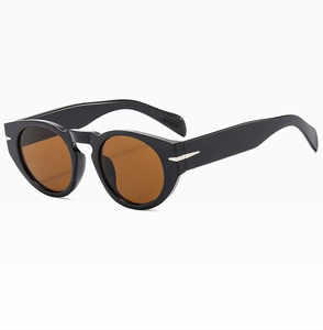 Detail of retro round sunglasses with black frames, brown lenses, and silver arrow accents
