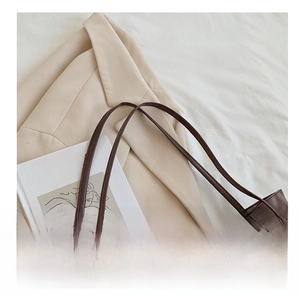 Detail of dark brown leather tote bag showing gold magnetic closure and soft texture