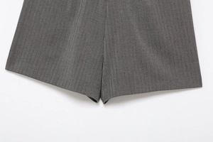 Detail shot of grey herringbone fabric texture on pleated shorts with professional finish