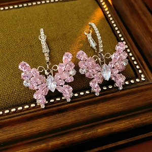 Macro detail of silver butterfly earrings with pink cubic zirconia on velvet