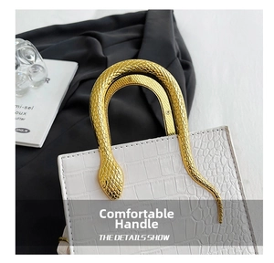 Close-up of white crocodile pattern handbag with luxury golden snake metal handle detail