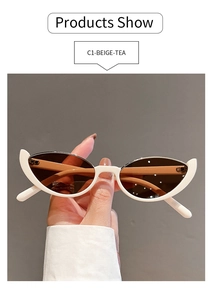 Detailed view of beige cat-eye sunglasses with tea lenses held against a grey background